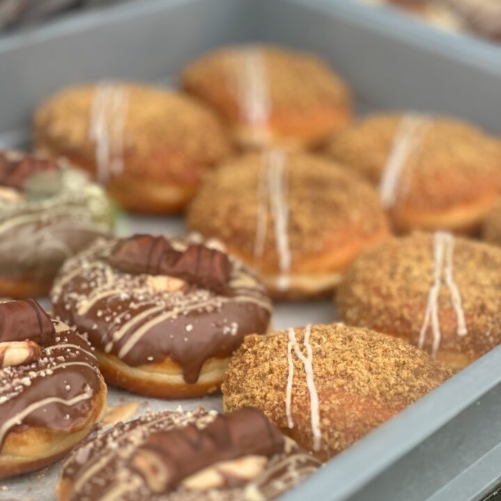 A tray of assorted donuts with chocolate, cream, and crumb toppings.